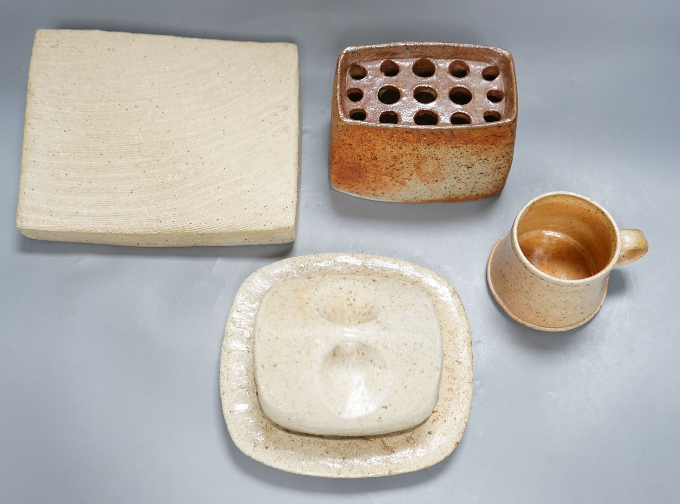 Sarah Walton (b.1945), a salt glazed stoneware flower brick, together with a salt glazed butter dish and cover, a similar mug, and a ‘Field’ horizontally carved linear slab, 22cm wide, all with impressed marks, (4)
